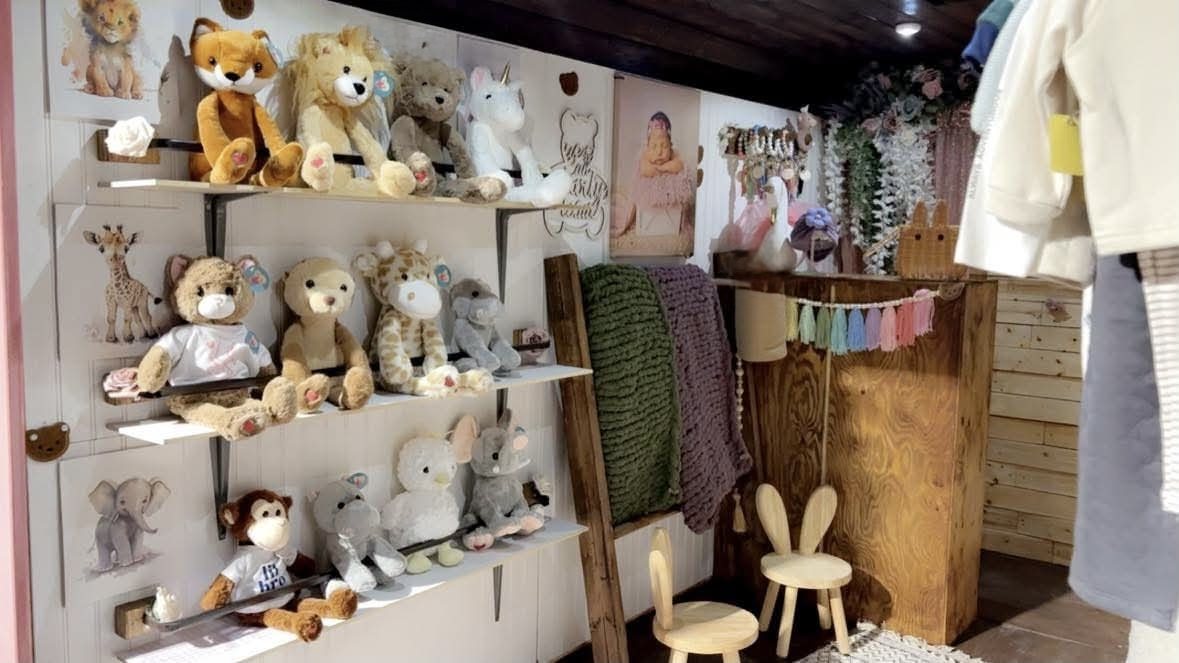 The Baby Beats studio: shelves of plush animals, knit blankets and hanging baby clothes in a warm wood-panelled space.